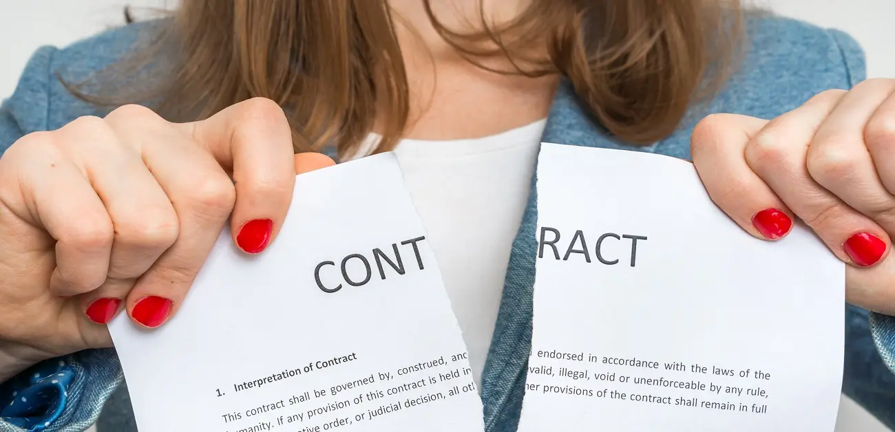 A woman with red nails tears a contract in half, symbolizing a decisive break or disagreement.