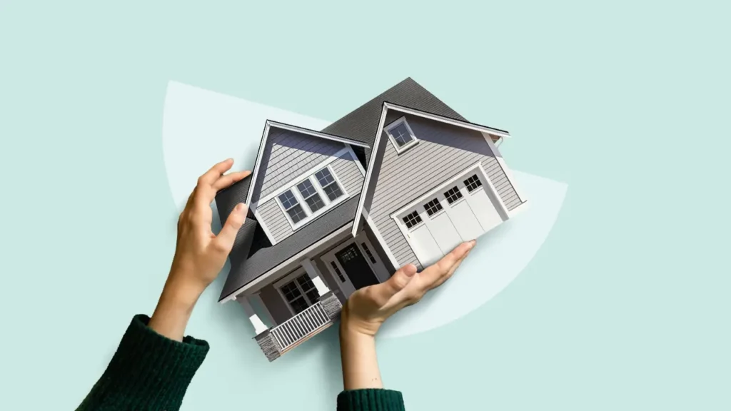 Two hands gently holding a 3D model of a modern house against a light mint green background.
