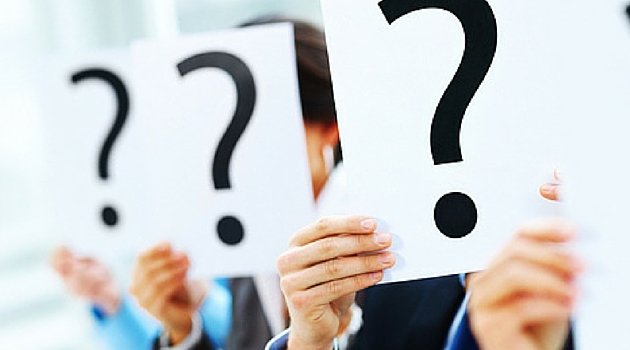 People holding large sheets of paper with bold question marks, suggesting curiosity or uncertainty in a professional setting.