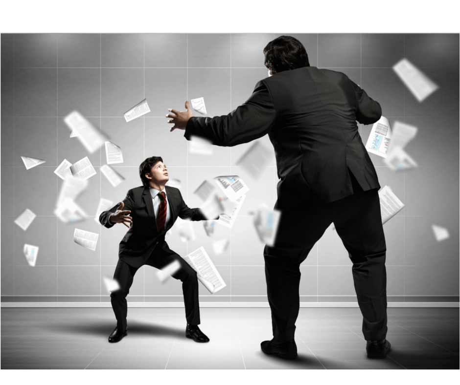 A tall man in a suit angrily gestures while a smaller man in a suit crouches defensively, surrounded by flying papers in a gray office setting.