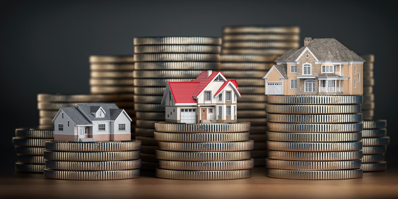 Three miniature houses atop stacks of gold coins, symbolizing real estate Commission and financial growth.