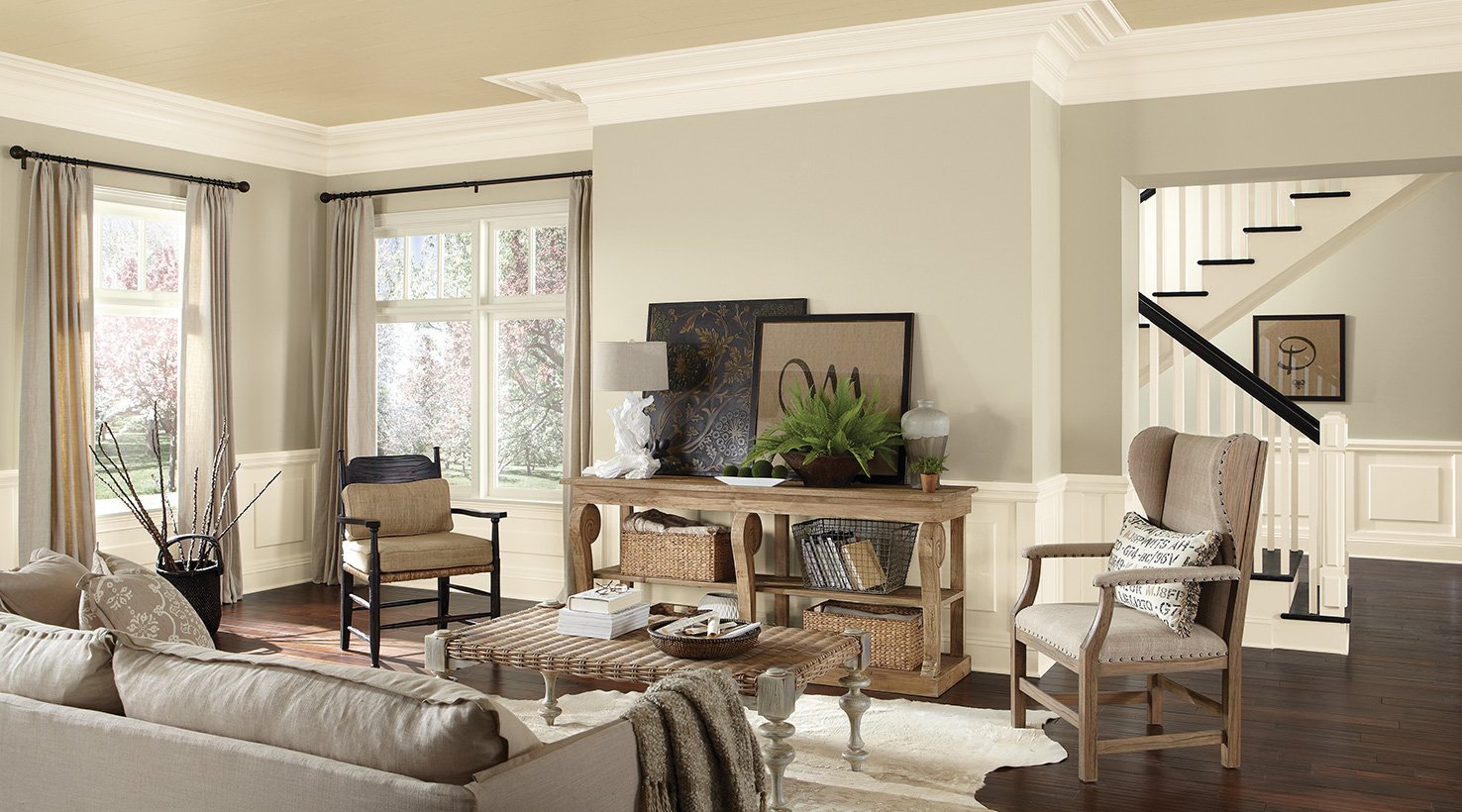 Bright, inviting living room featuring a neutral palette, stylish furniture, and large windows showcasing outdoor greenery.